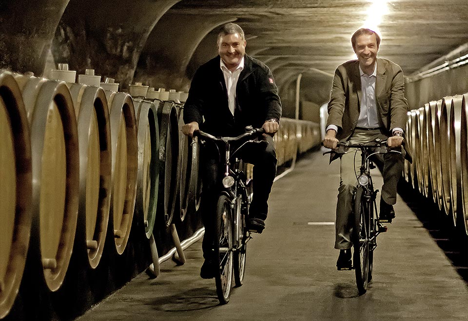 Directeur Dr. Kartsen Weyand und kellermeister Johannes Becker fietsend door de gewelven in Trier